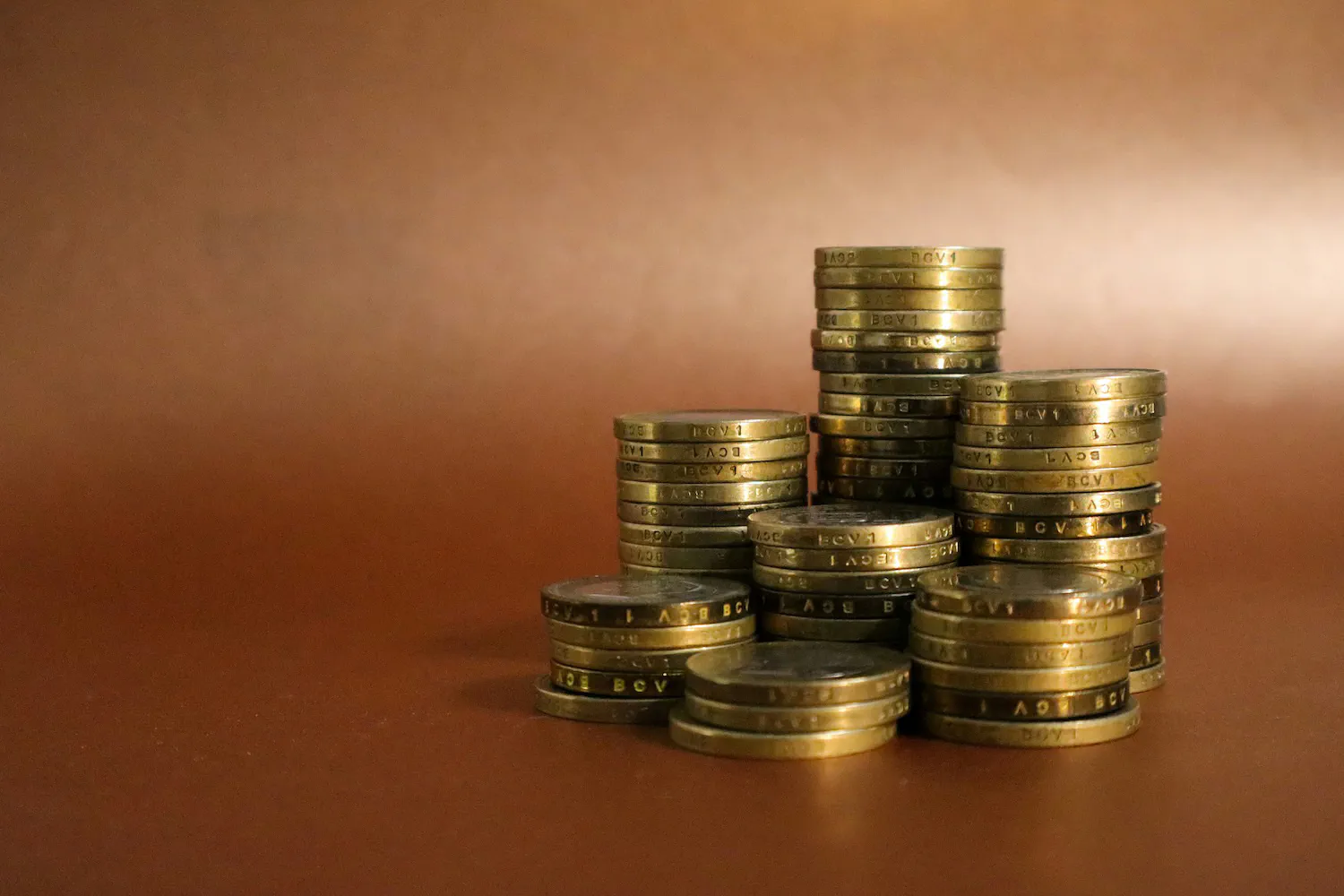 Gold coin stacks representing the high capital cost of running the Wheel on index ETFs